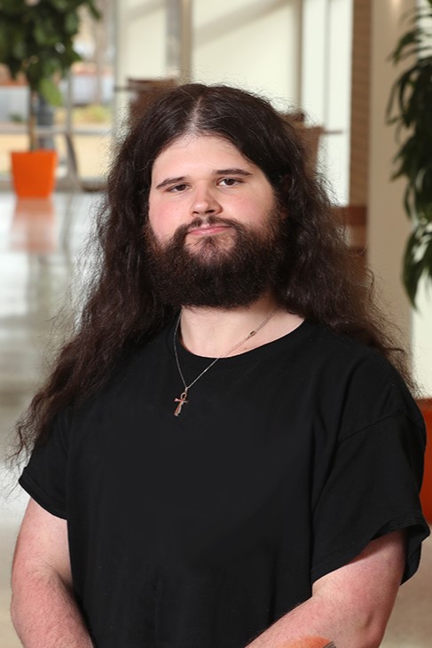 bearded palaeontology researcher with black t shirt and long hair