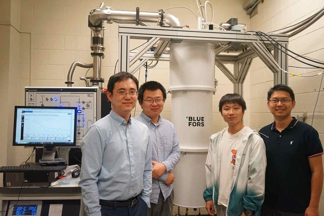 four scientists standing in front of fridge in lab quantum
