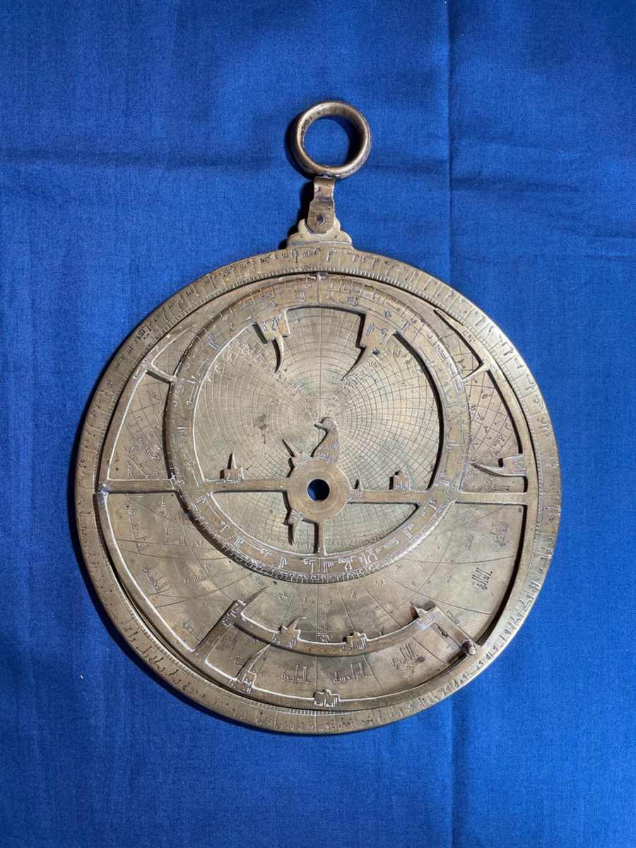 An ancient astrolabe rests on blue cloth