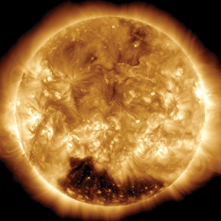 2015 showing the coronal hole as a dark region in the south.  Coronal holes are regions of the corona where the magnetic field reaches out into space rather than looping back down onto the surface. Particles moving along those magnetic fields can leave the Sun rather than being trapped near the surface. Those trapped particles can heat up and glow