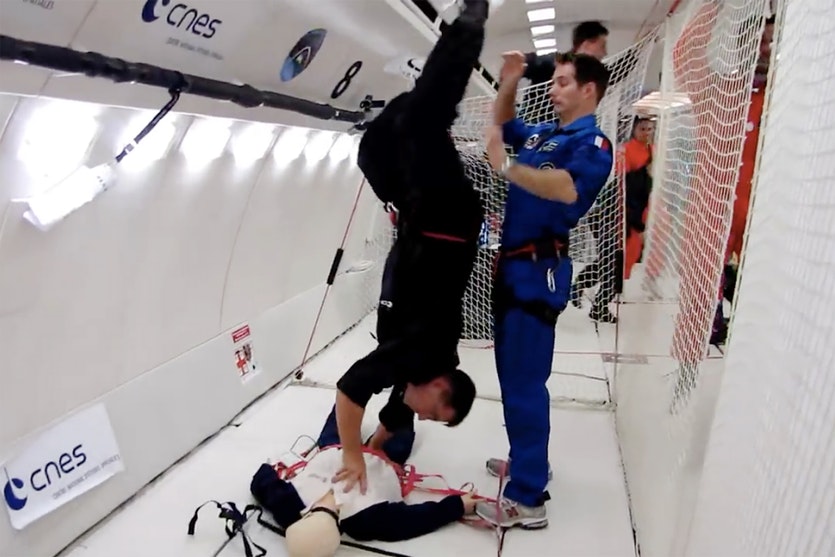 An astronaut demonstrates a handstand cpr technique in a simulated low-gravity environment.