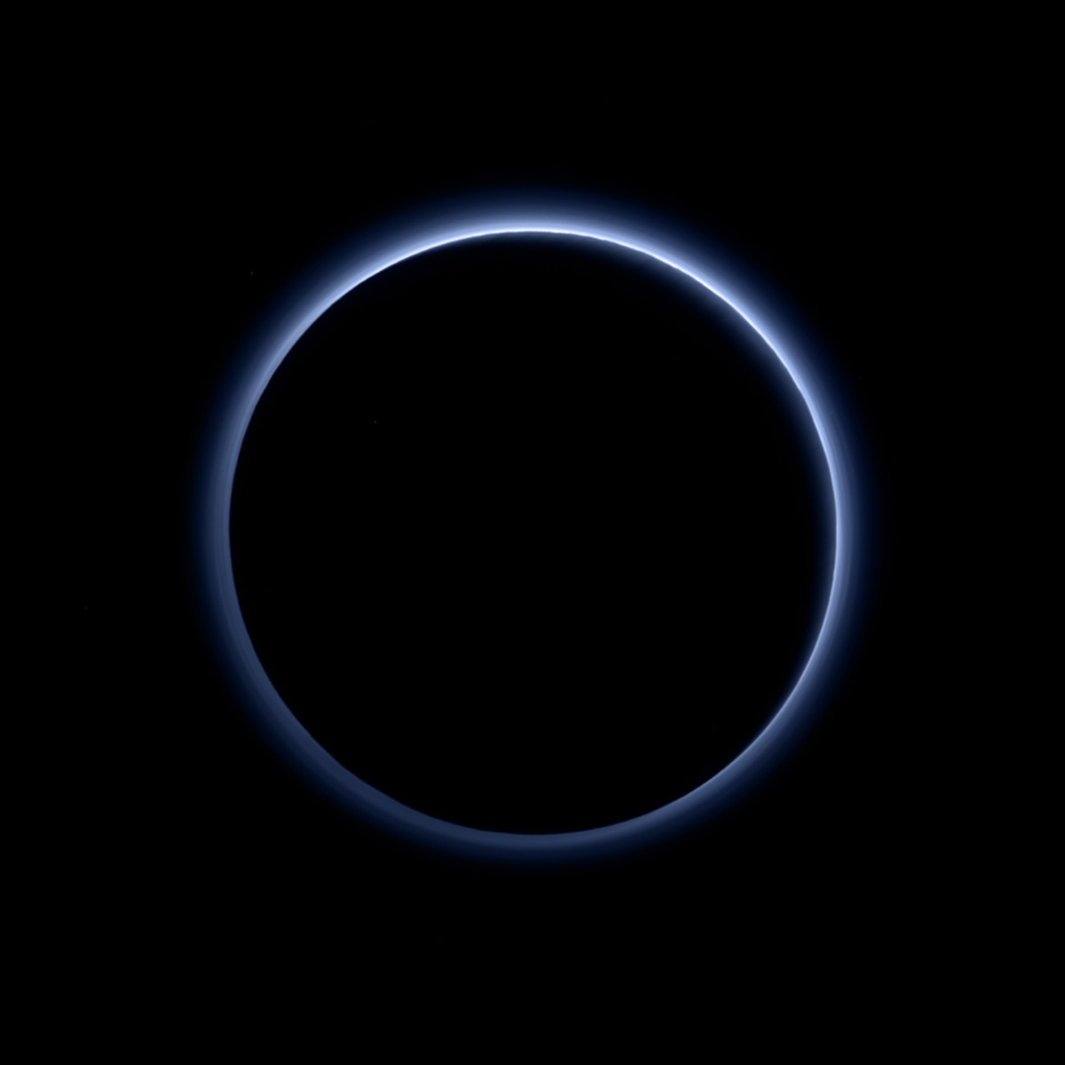 Pluto's blue haze is visible in this New Horizons photo looking back at the dwarf planet with the Sun behind it.