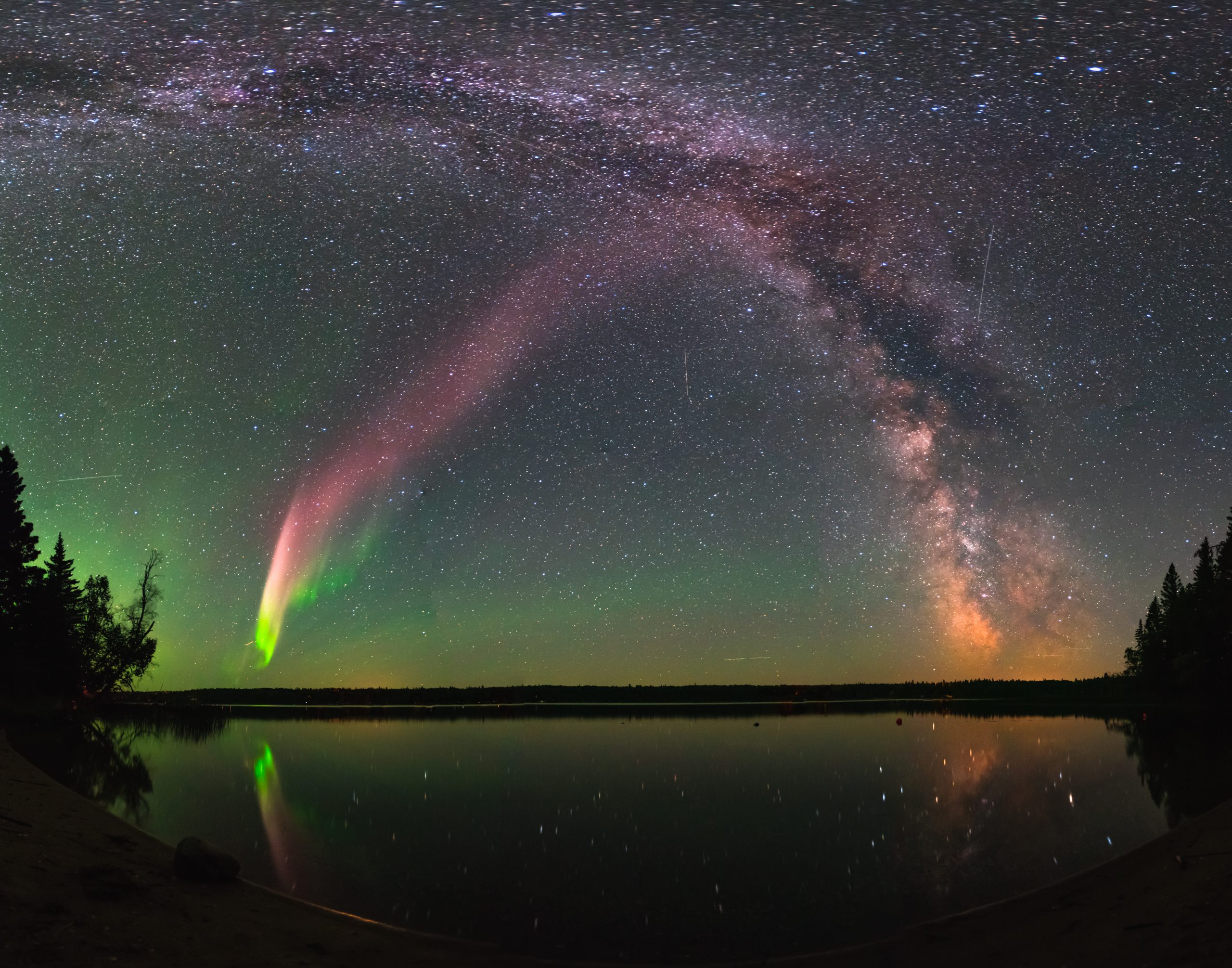 A composite image show the ‘steve’ aurora and the milky way over childs lake, manitoba, canada.