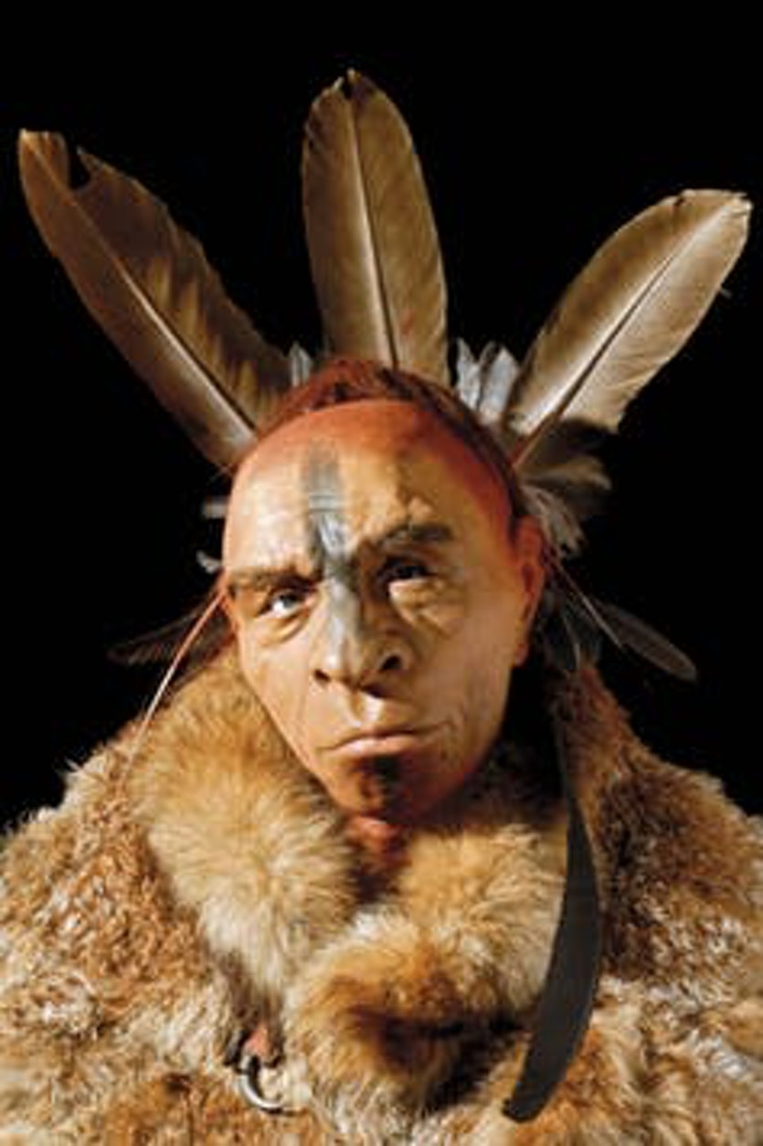 Reconstruction of a neanderthal man wearing body paint and eagle feathers.