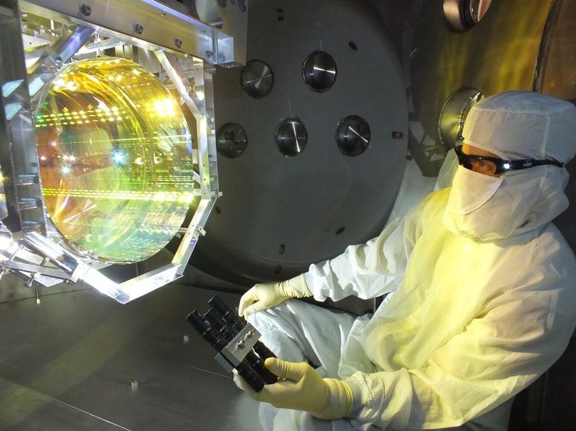 Before sealing up the chamber and pumping the vacuum system down, a ligo optics technician inspects one of ligo’s core optics (mirrors) by illuminating its surface with light at a glancing angle.