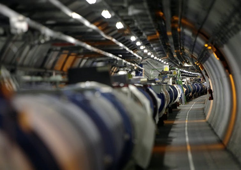 View of the lhc in its tunnel at cern (european particle physics laboratory) near geneva, switzerland. The lhc is a 27-kilometre-long underground ring of superconducting magnets housed in this pipe-like structure, or cryostat. The cryostat is cooled by liquid helium to keep it at an operating temperature just above absolute zero. It will accelerate two counterrotating beam of protons to an energy of 7 tera-electron volts (tev) and then bring them to collide head-on. Several detectors are being built around the lhc to detect the various particles produced by the collision.