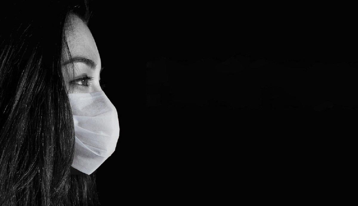 black and white image of woman in profile wearing a surgical mask