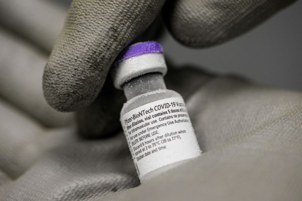 Close up of hands holding a vial of pfizer biontech vaccine