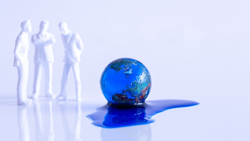 Globe marble and blue liquid on a white table. Tree persons (white figures) discussing and trying to find a solution.