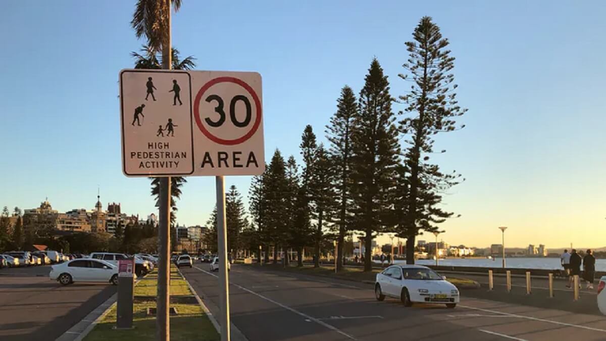 A road near a beach with a speed limit sign restricting vehicles to 30km/h