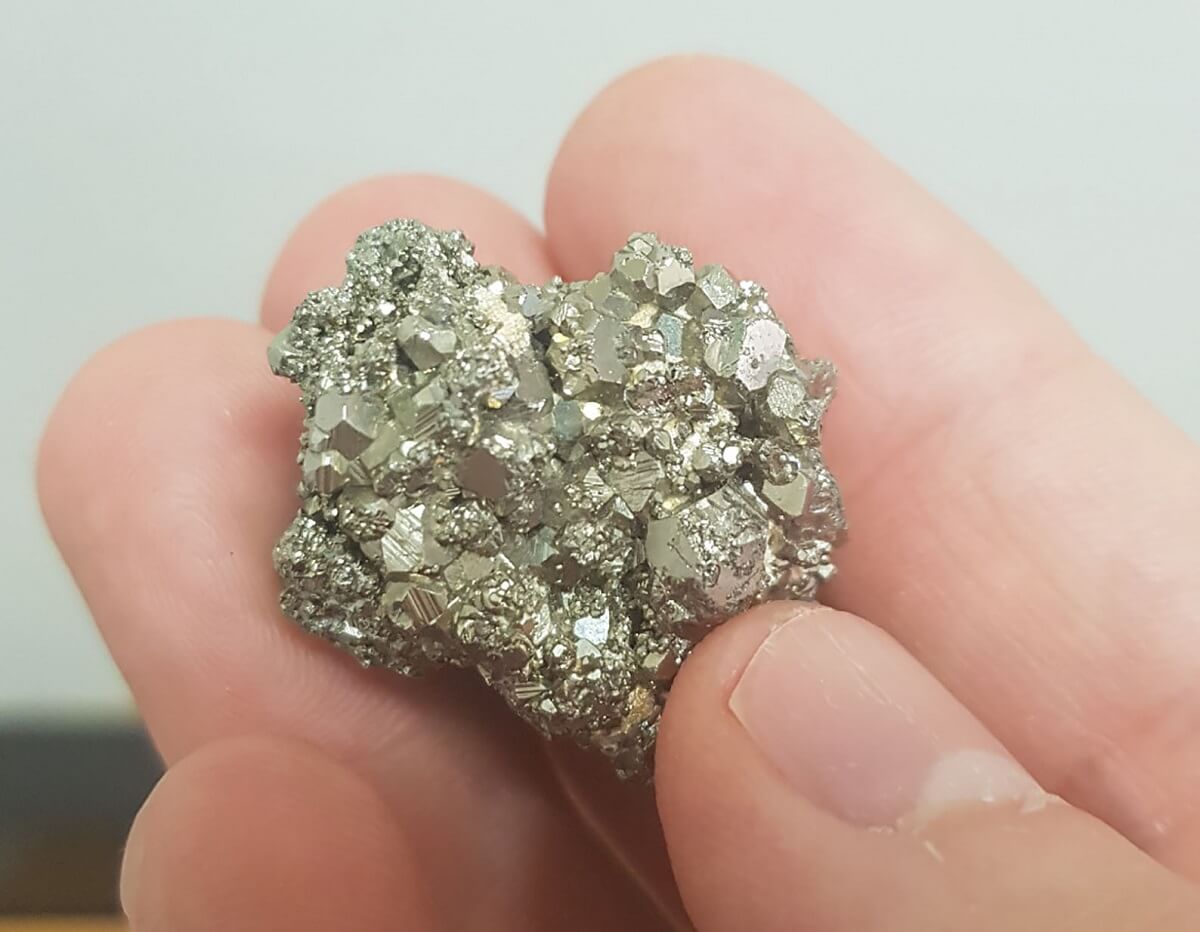 A hand holding the mineral pyrite.