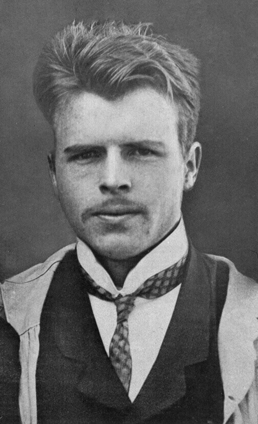 A man ina black and white photo. He has pale skin and medium shaded hair and a moustache
