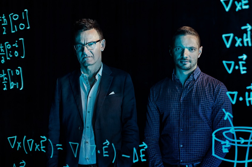 Andrew dzurak and jarryd pla behind a glass screen with glowing equations