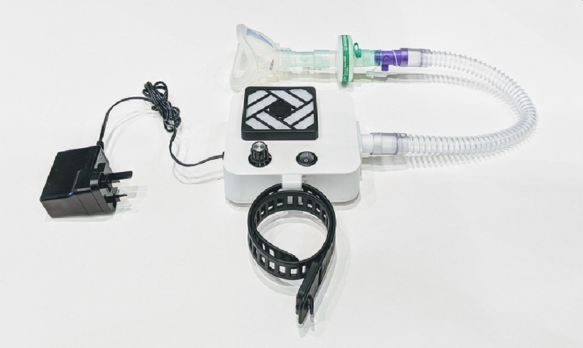 Photo of a breathing device, with a fan, tube attached to face mask, electric plug and strap for securing