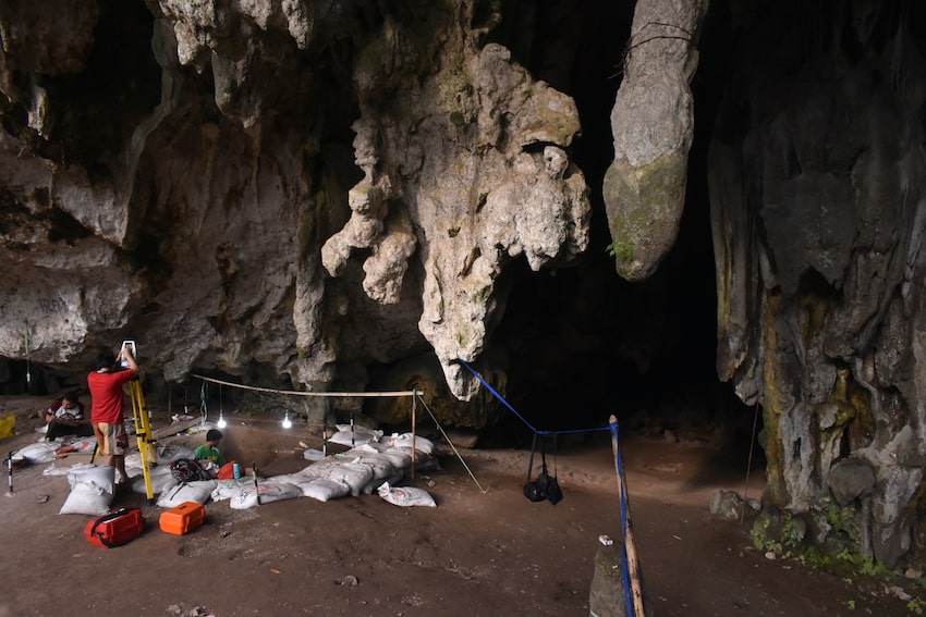 Excavations at leang panninge cave, showing researchers under overhanging rock.