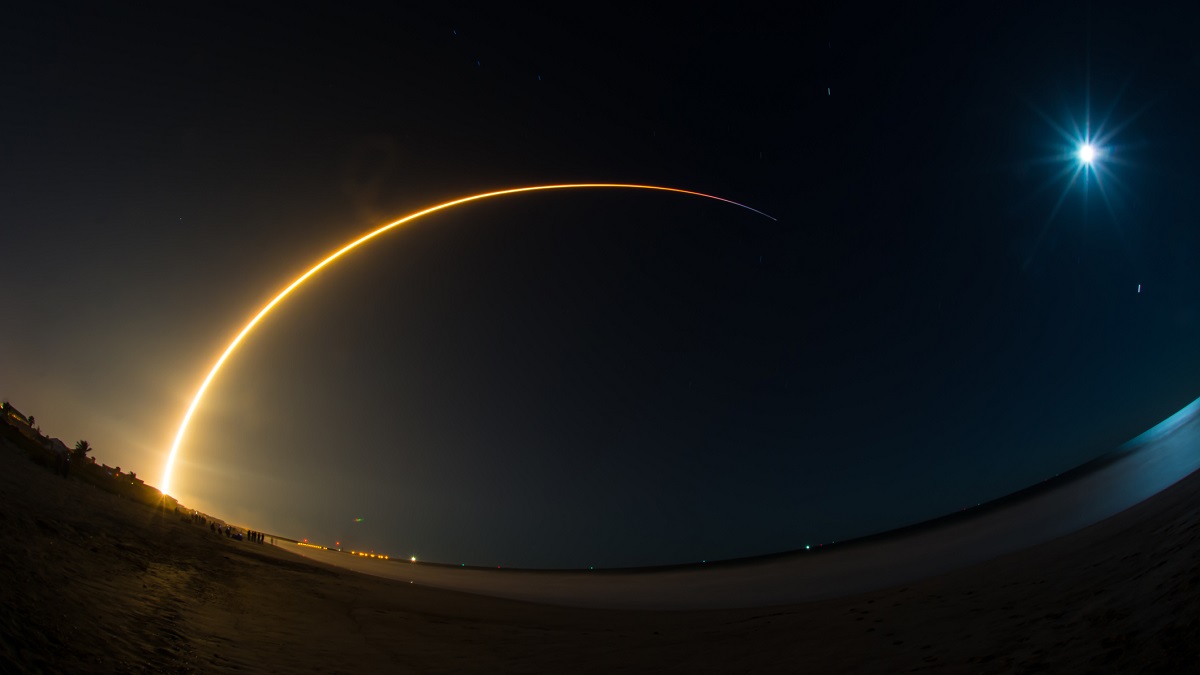 A rocket launching at night, causing a streak of light across a black sky.