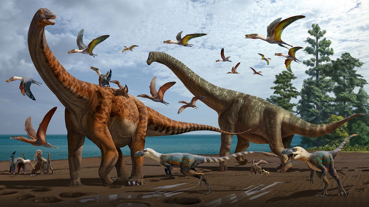 Illustration of two huge long neck dinosaurs, with pterosaurs flying around. There are on the beach. There are some green trees at the back and clouds in the sky. There are some small two legged dinosaurs on the ground next to them