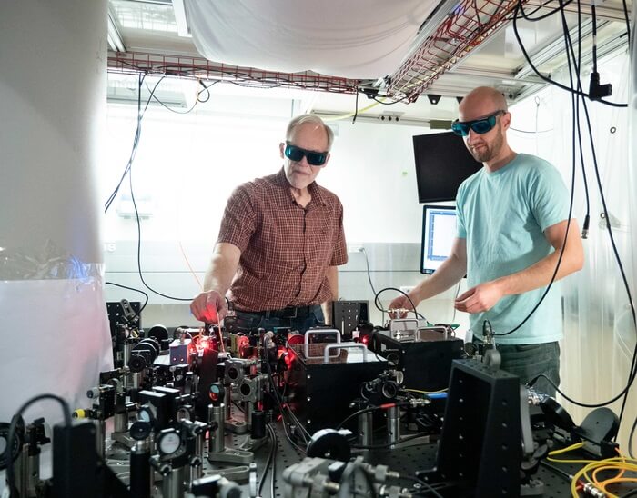 Two physicists in a lab wearing sunglasses, working with lasers.
