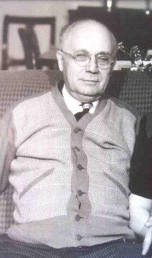 A man with glasses wearing a cardigan