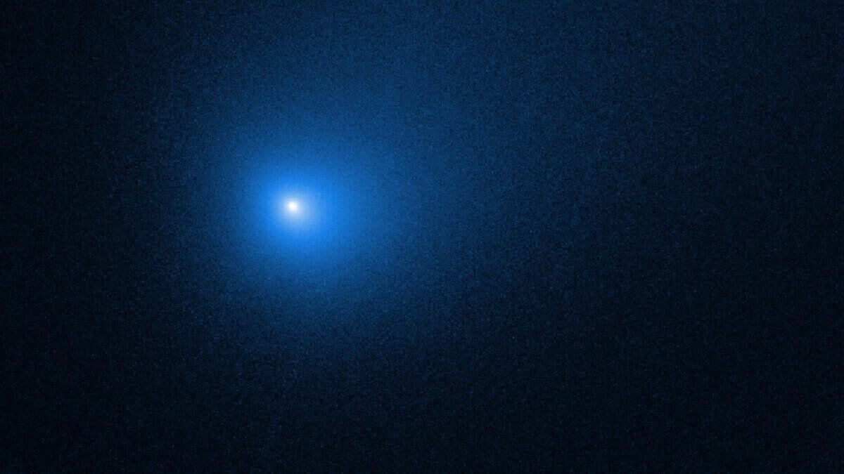 An image of an interstellar comet: a bright blue fuzzy dot among a black background