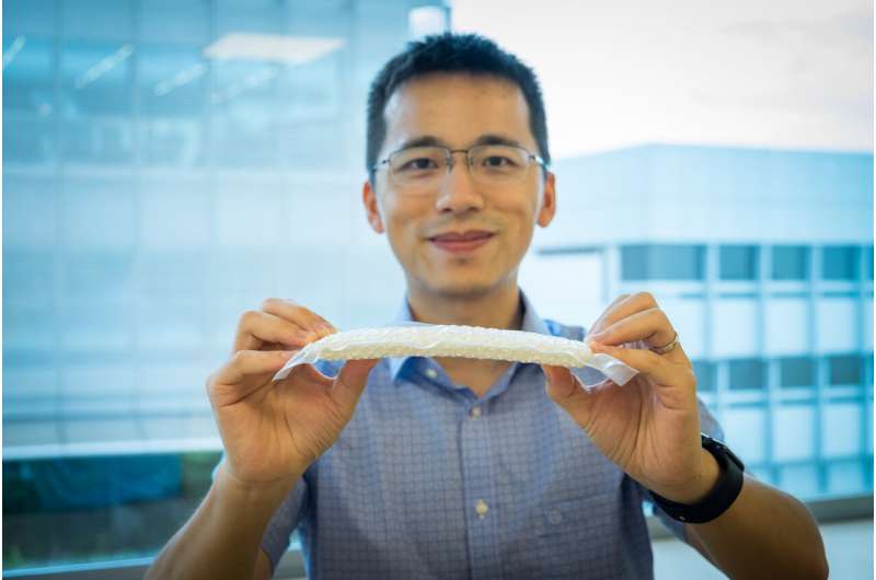 Man holding a flat material in a plastic sleeve.
