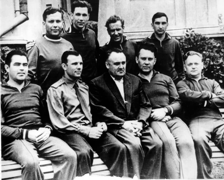 A black and white men of nine men posing for a photo