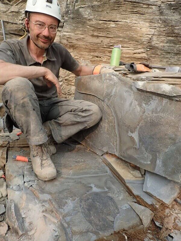 Man in a helmet sitting on a fossil slab