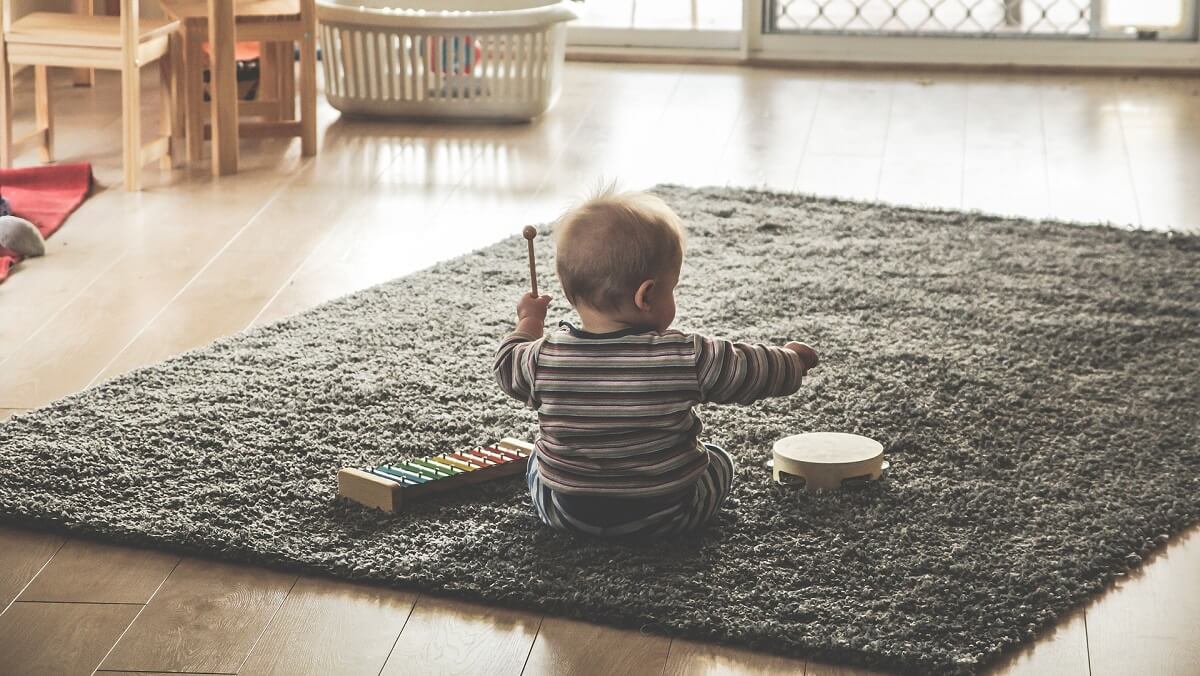 a baby sitting on a rug. It is playing a xylaphone