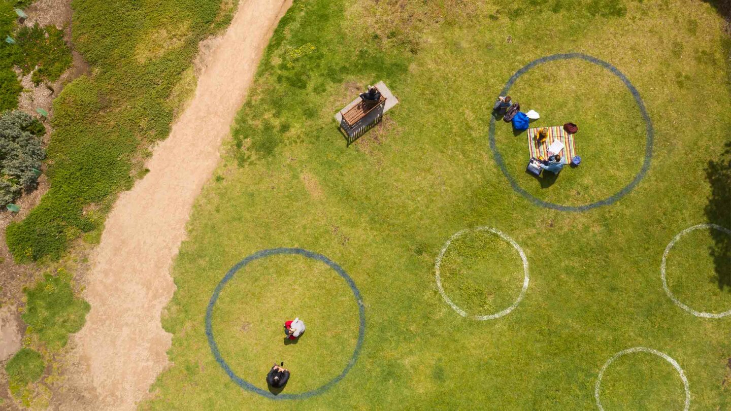 aerial view of people inside circles drawn on the grass in a park