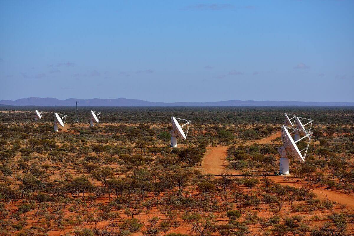 Five white antennas of the askap radio telescope, in the desert.