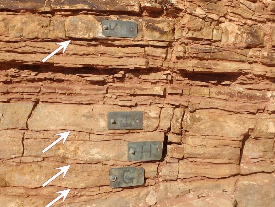 Four pieces of metal nailed into layers of red rock