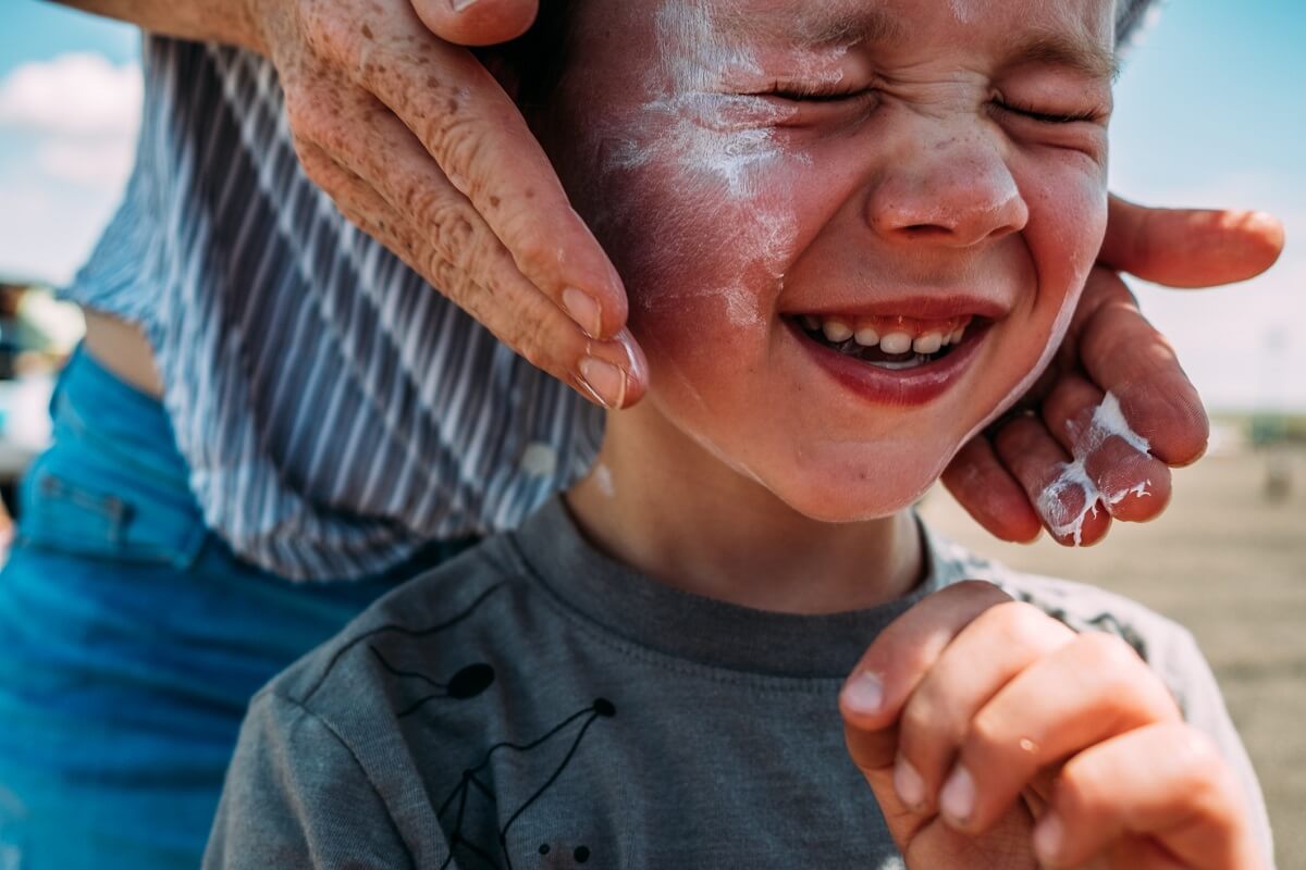 Close up of mom's hands applying lotion on boys face