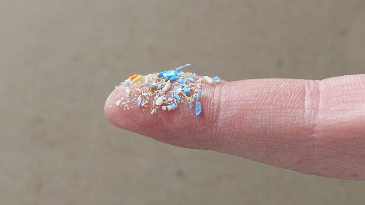 Close up side shot of microplastics on human finger.