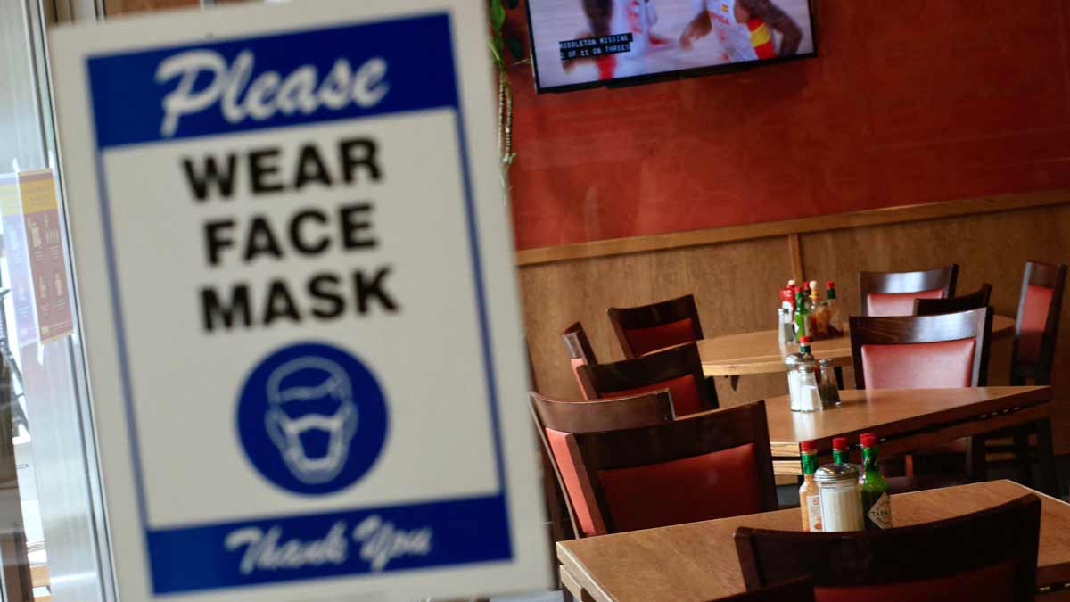 empty restaurant with sign requiring face masks on the door