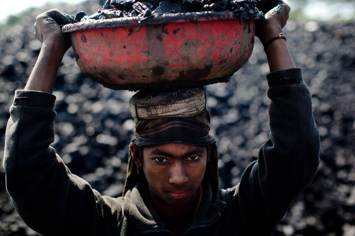 Boy holds a tub of coal on his head