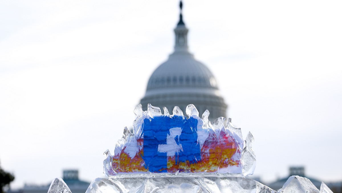 an iceblock with a facebook symbol inside it. The iceblock is infront of a white building