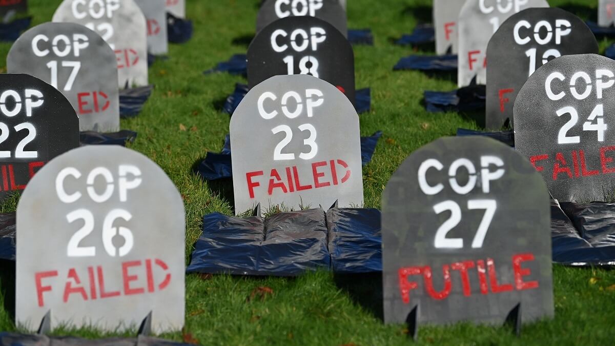 Rows of cardboard headstones. Front ones say "COP26: FAILED" and "COP27: FUTILE"