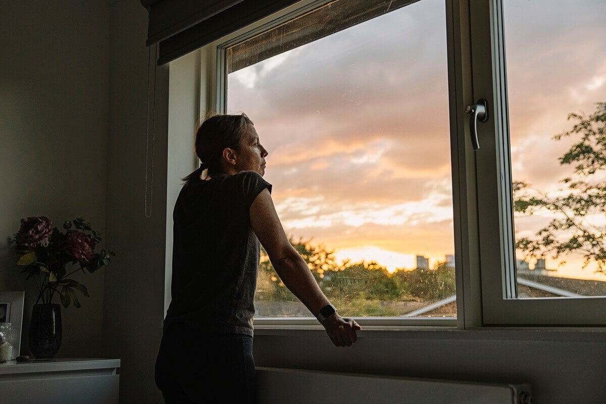 Woman looking out of window at sunset