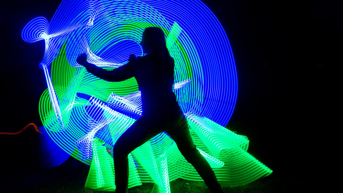 Silhouette of woman posed in front of blue and green lights