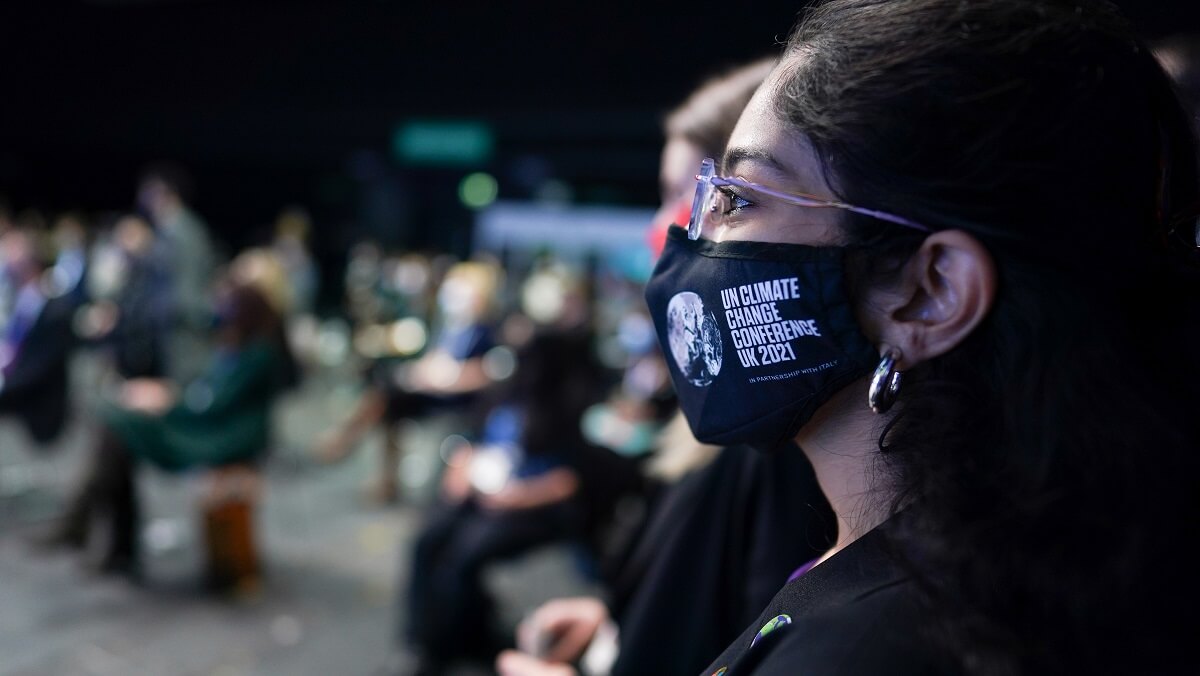 close up on a womans profile. She wears a mask that says UN Climate Change Conference UK2021