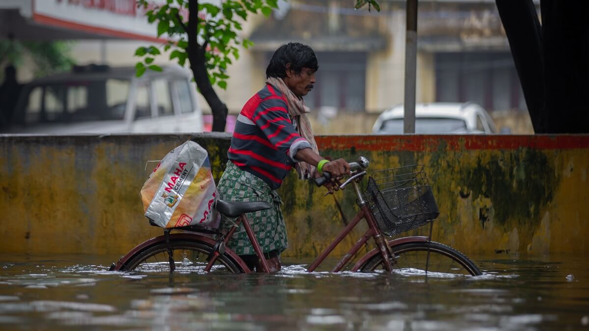 A man pushes a bicycle on a flooded street
