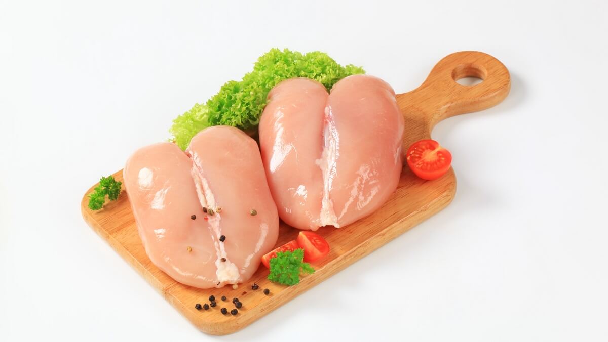 Raw chicken breasts on a wooden paddel
