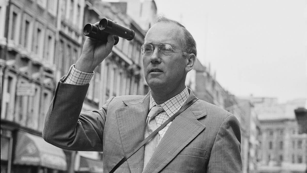 Charles Townes holding binoculars on a street
