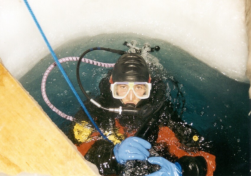 Women in scuba gear in an ice hole