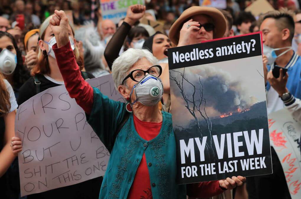 Masked protestor (elderly woman) holding sign