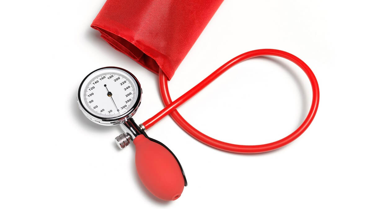 red sphygmomanometer, or blood pressure gauge, against white background