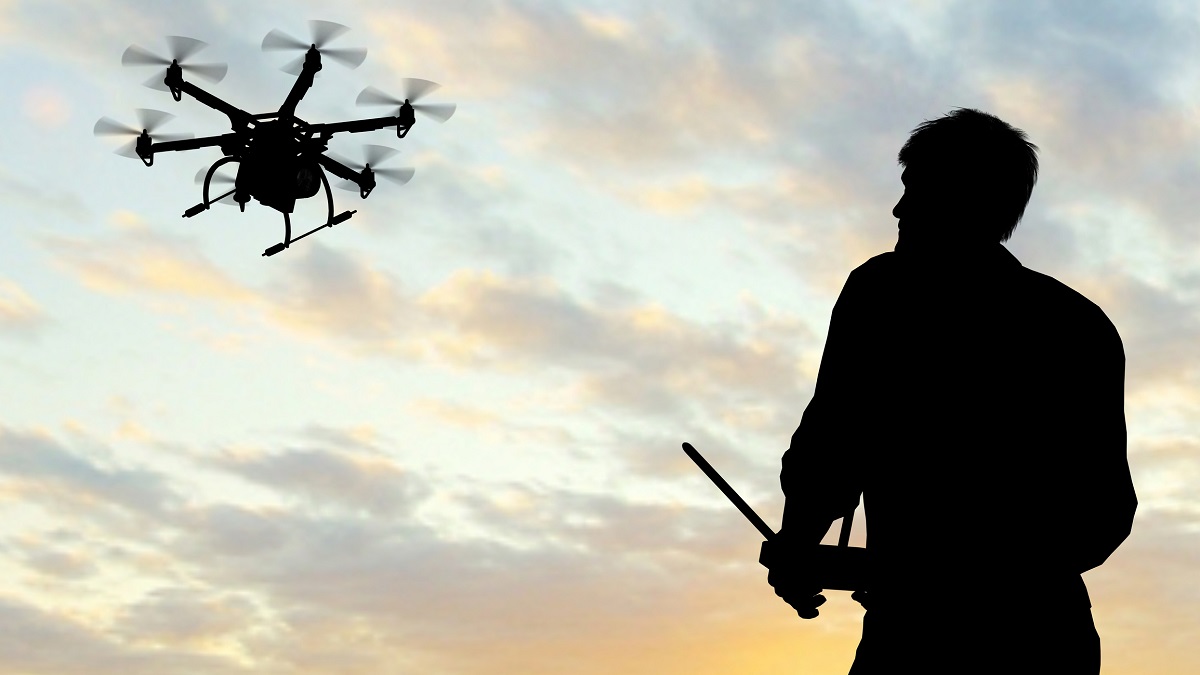 man operating drone against sunset