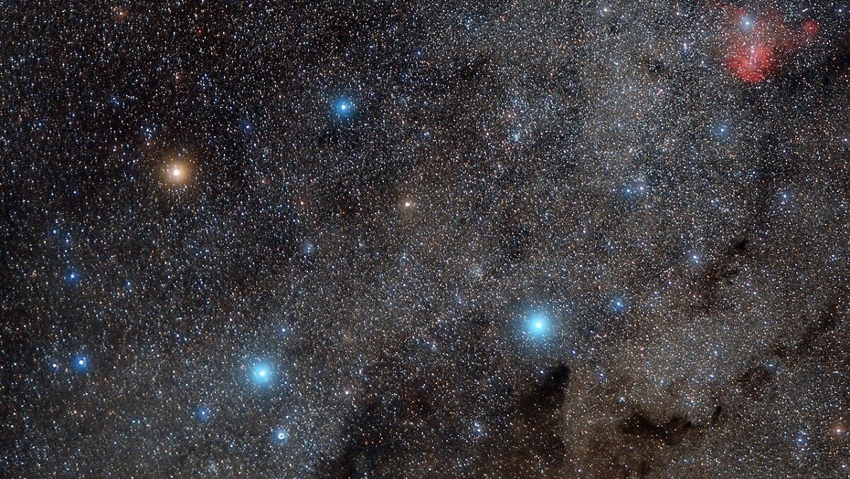 four bright stars in the night sky. One is orange, 3 are blue.