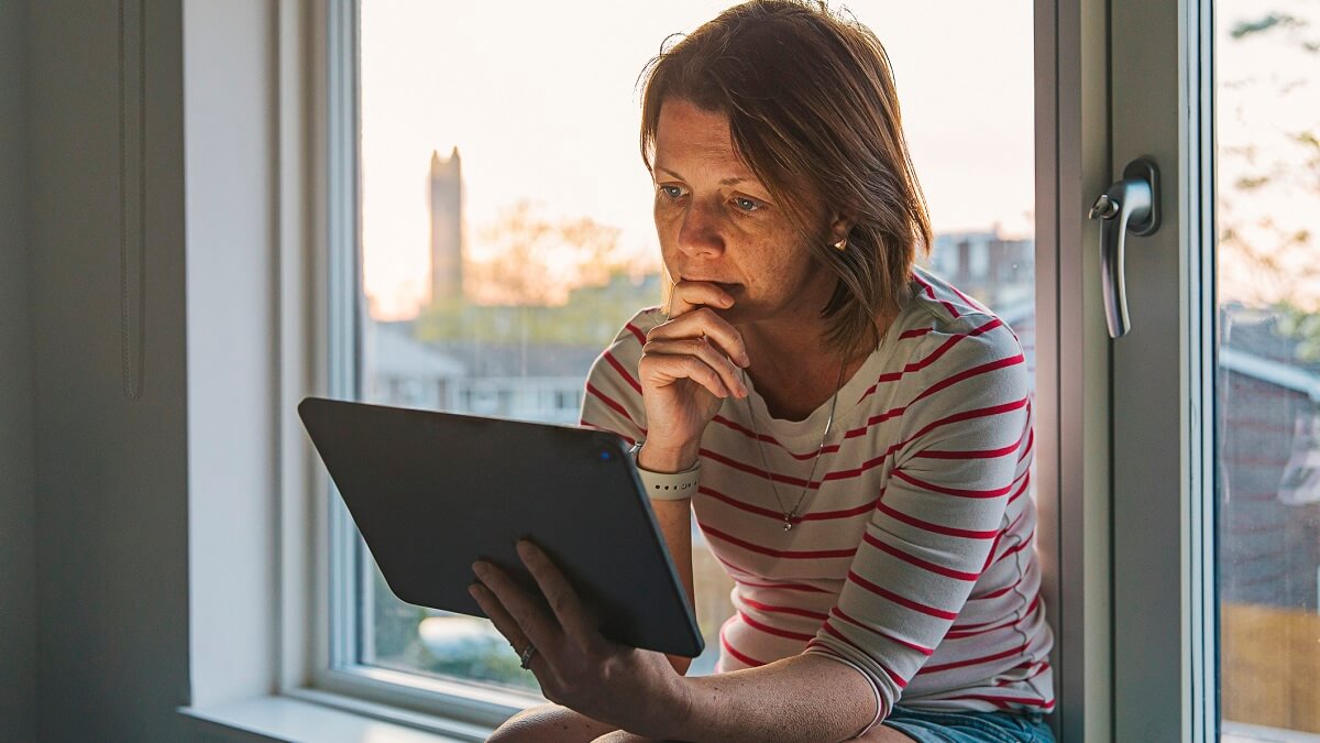 Woman using digital tablet on window sill