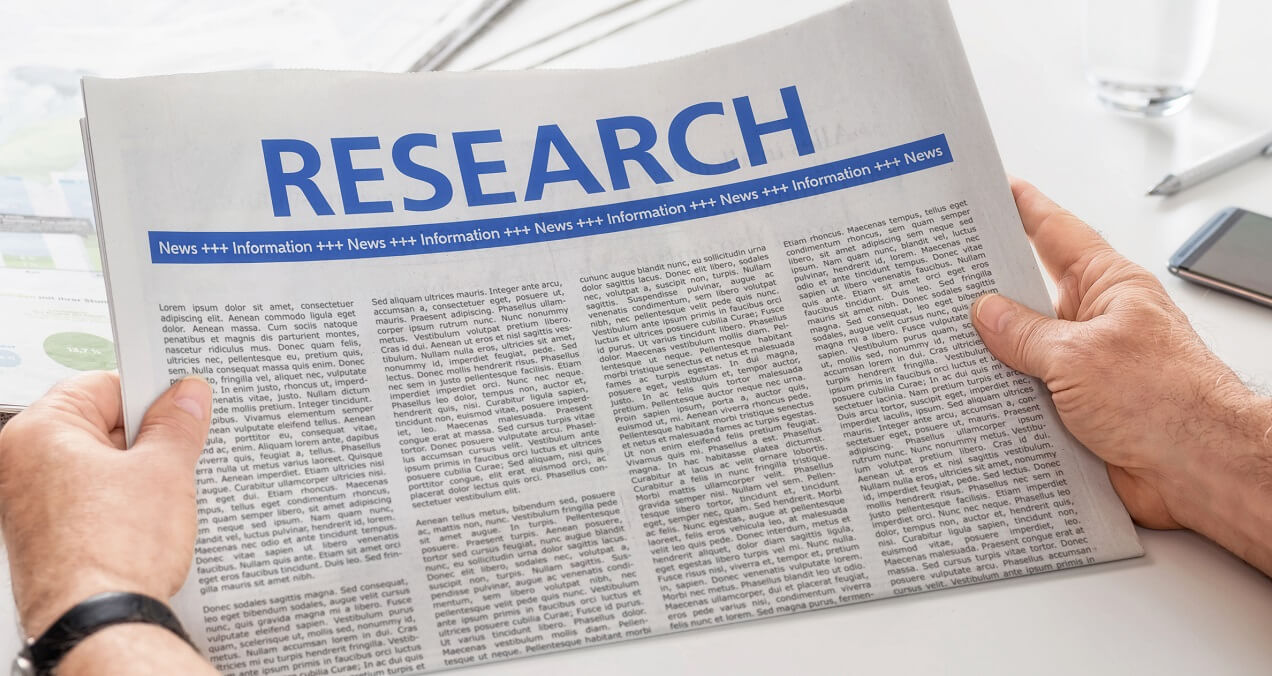 Man reading newspaper with the headline Research -